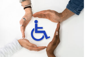 emploi et formation Image coupée en deux : à gauche, quatre mains forment un cercle protecteur autour du pictogramme bleu du handicap ; à droite, une personne en fauteuil roulant remplit un formulaire écrit sur un bureau.