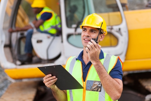 Chef de chantier en gilet jaune avec talkie-walkie sur un chantier de travaux publics